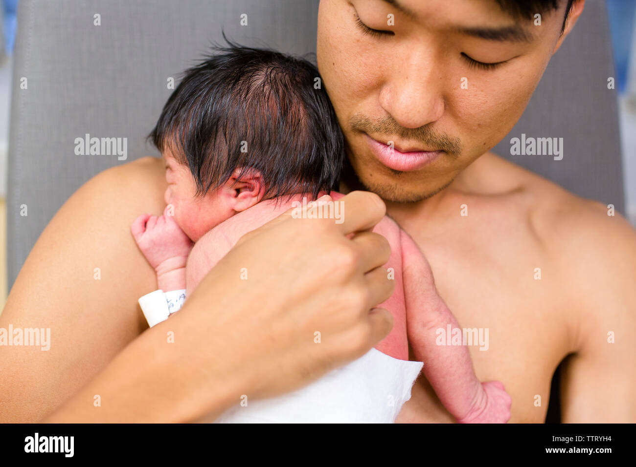 a new father rests peacefully skin-to-skin with his newborn baby girl Stock Photo