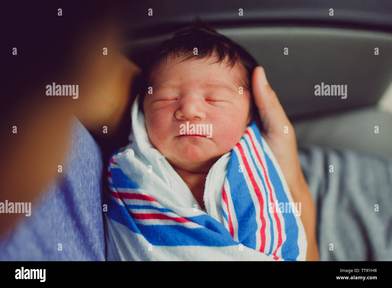 a close-up view of a newborn baby wrapped cradled in her father's arms Stock Photo