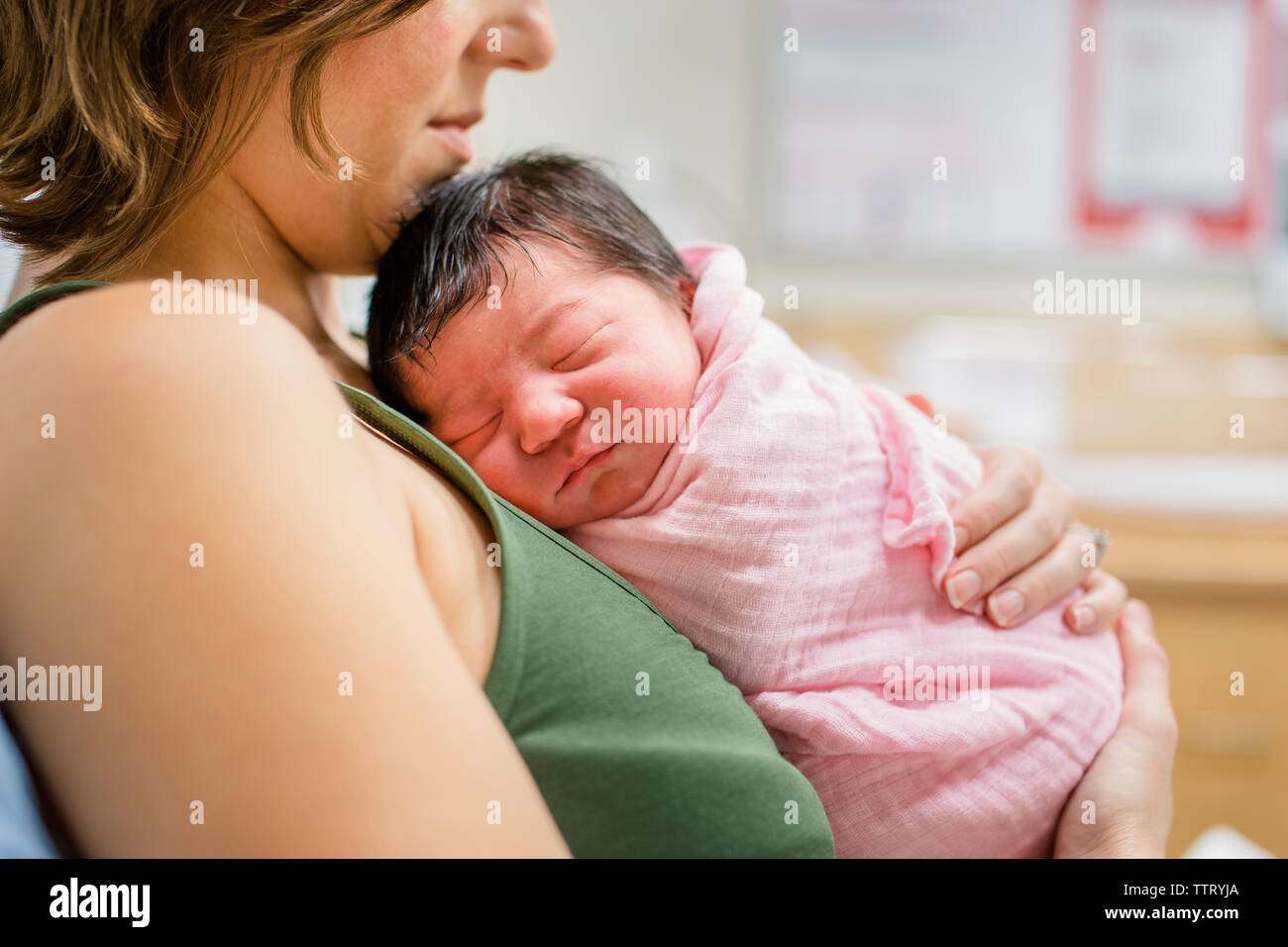 side view of a new mother cradling her newborn baby girl in hospital