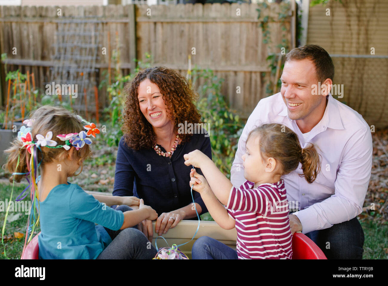Two little girls play while their parents look affectionately on Stock Photo