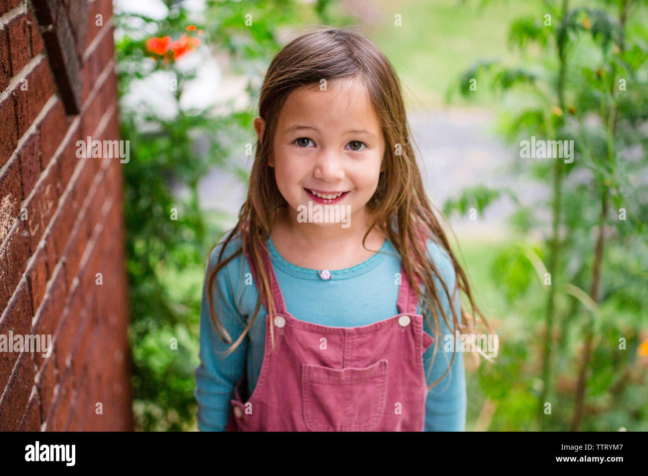 a happy little girl stands in a garden looking up Stock Photo - Alamy