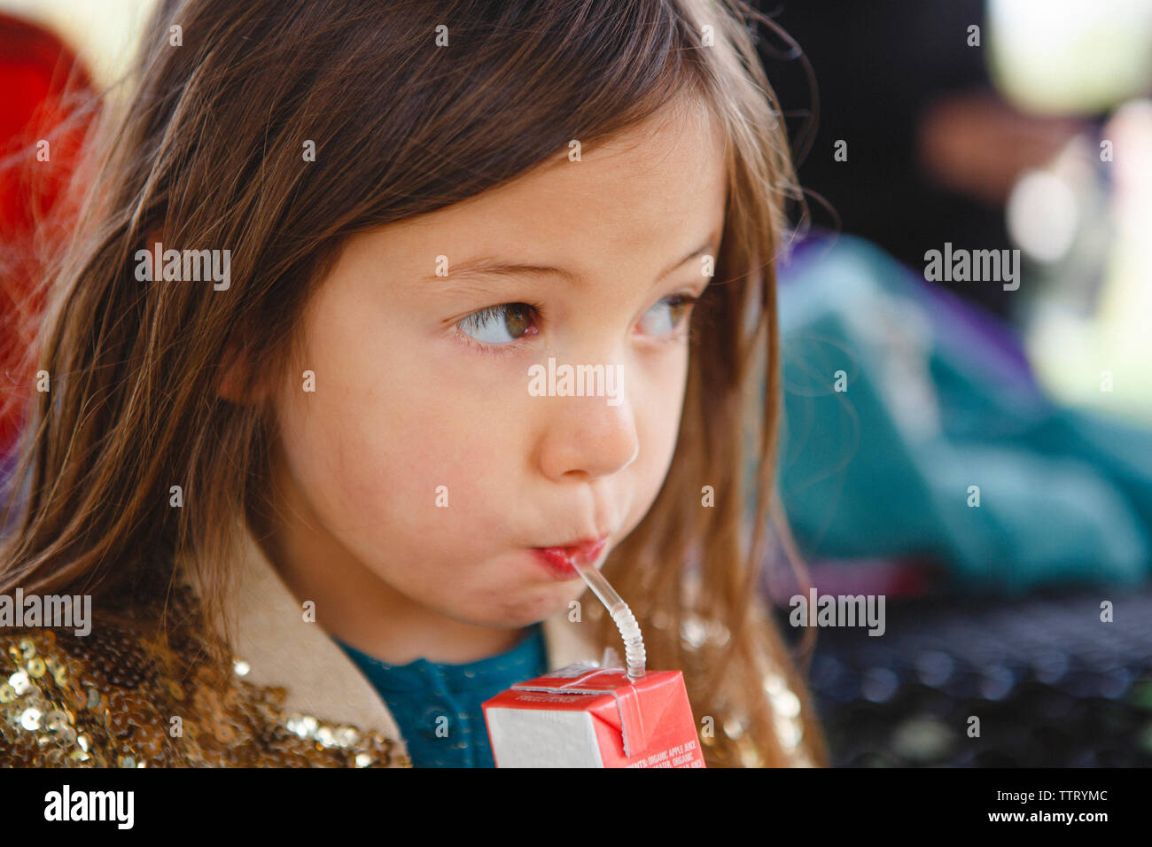 a cute little girl sips juice from a straw Stock Photo - Alamy