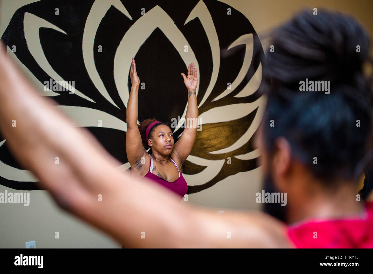 A woman in a yoga class stretches her arms up in a yoga pose Stock Photo