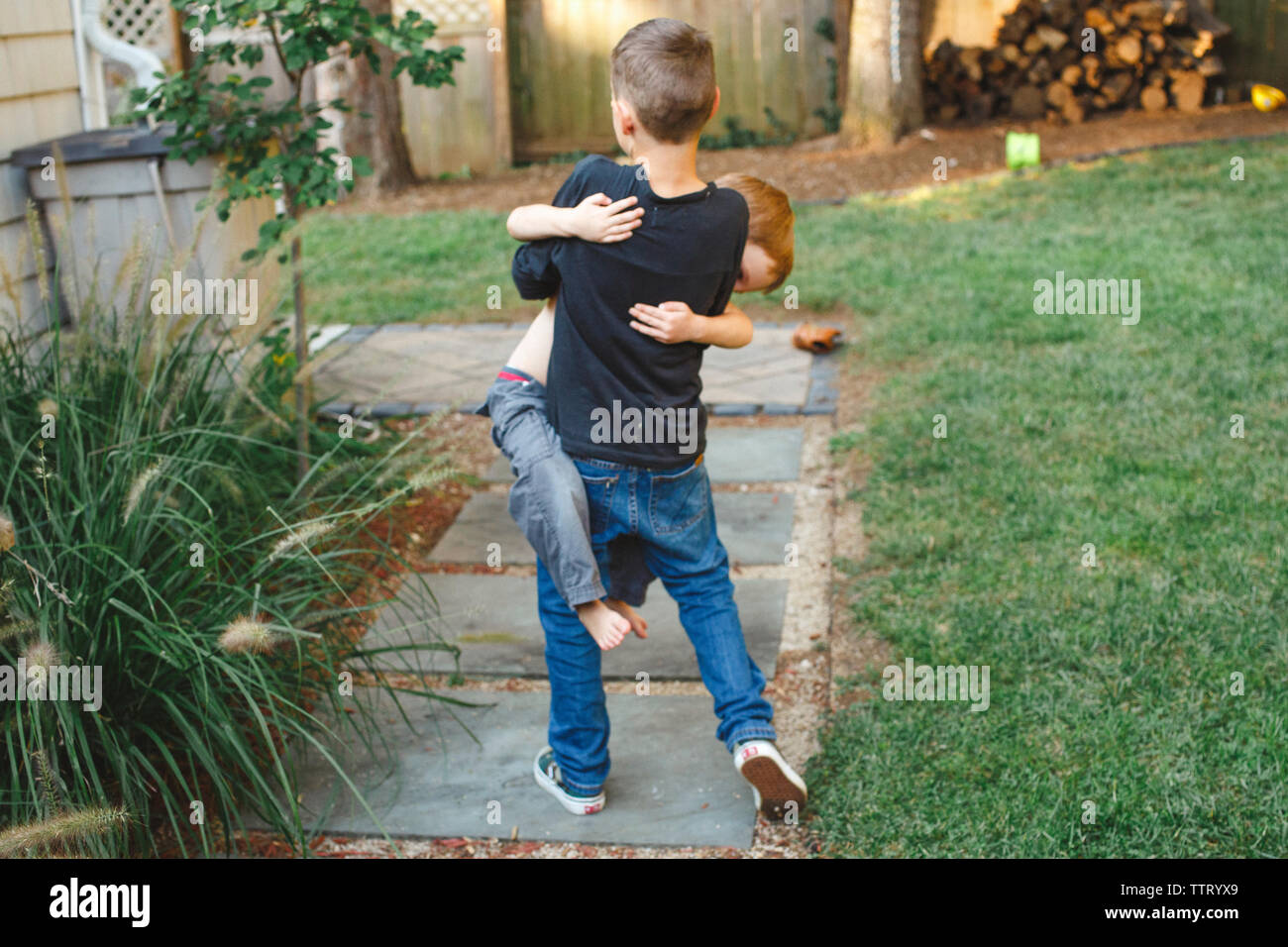 a young boy carries his little brother in his arms Stock Photo Alamy