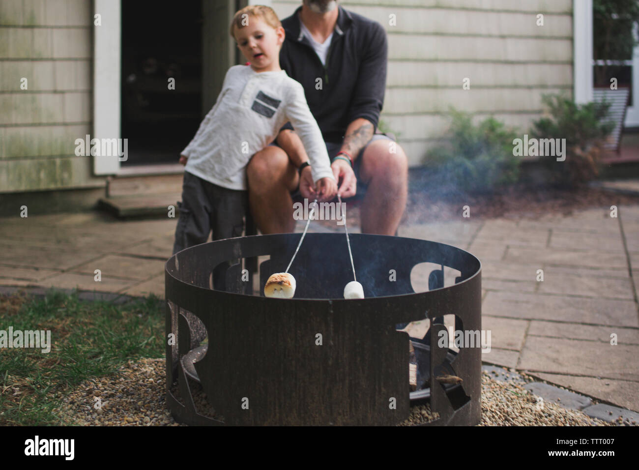 Bottom half of a father roasting marshmallows with his small child Stock Photo