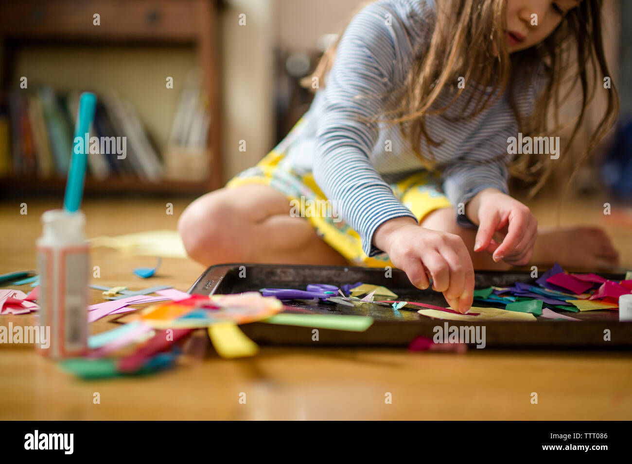 close up view of a small child making art on floor in window light Stock Photo