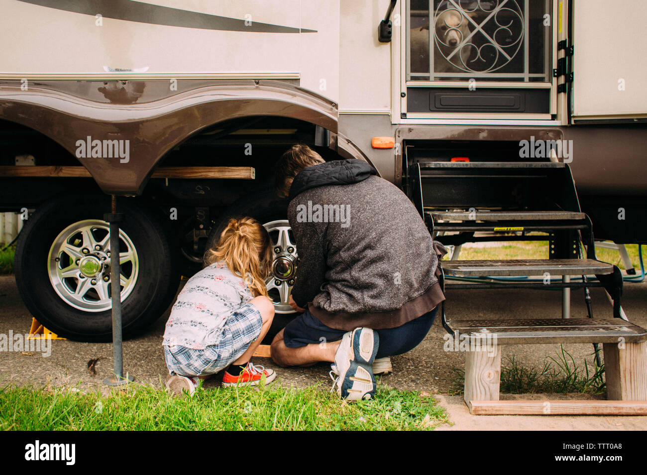 Rear view of father and daughter fixing tire Stock Photo
