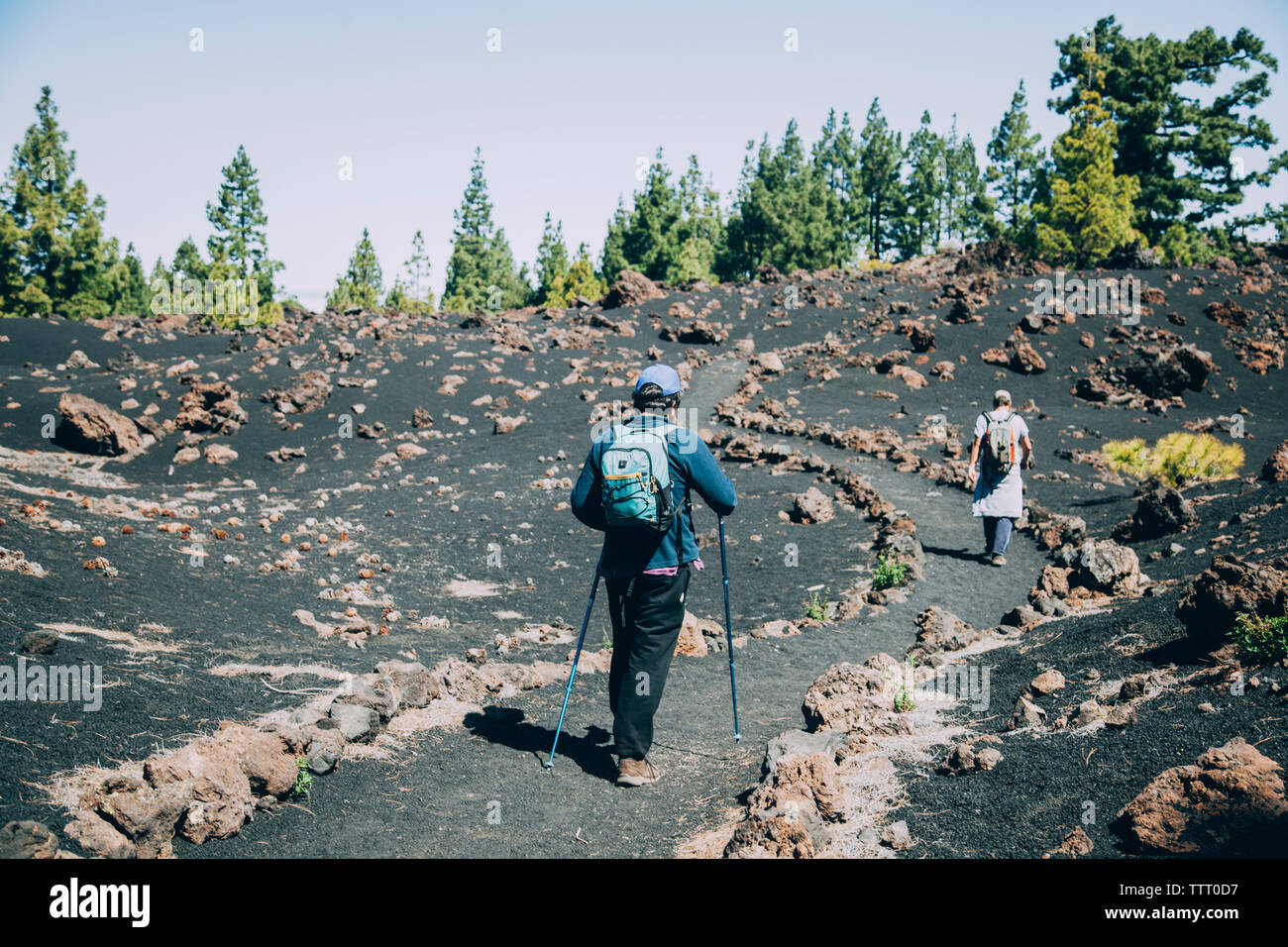 Two people walk on a path in a volcanic landscape, in Tenerife. Stock Photo