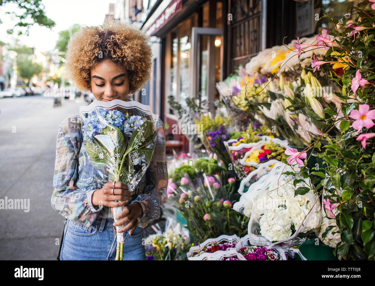 Smiling woman smelling hydrangeas outside flower shop Stock Photo