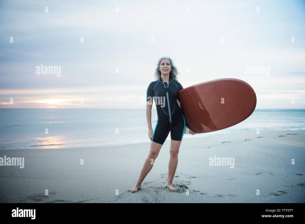 Full length portrait of confident female surfer carrying surfboard at Delray Beach Stock Photo