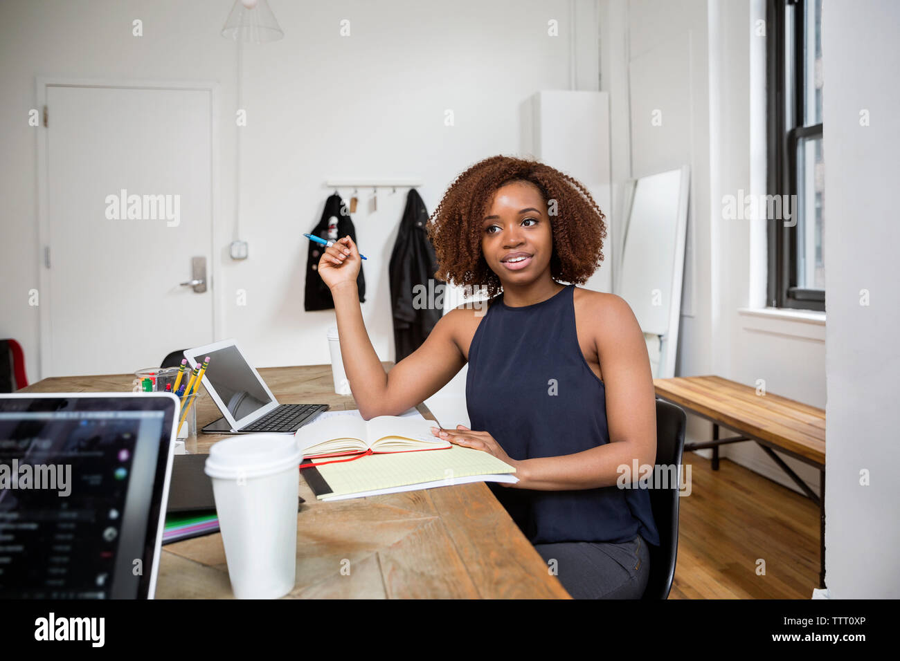 Confident businesswoman looking while sitting at desk in creative office Stock Photo