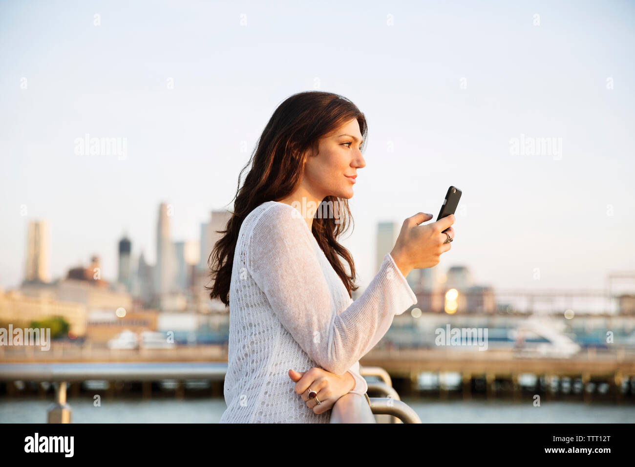 Side view of woman holding smart phone while standing at