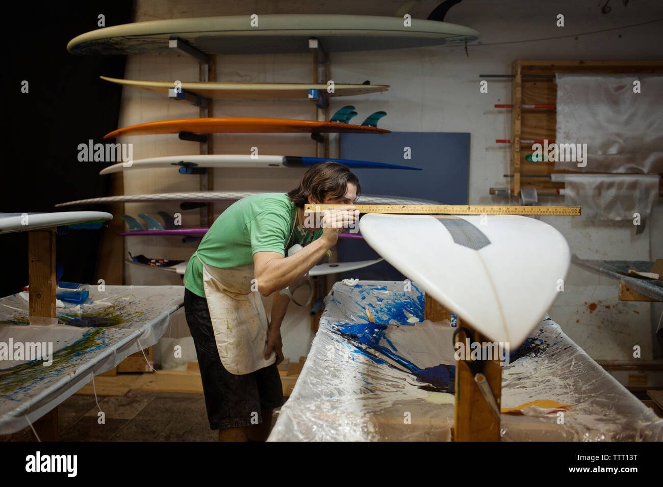 worker using ruler to measure surfboard in workshop Stock Photo