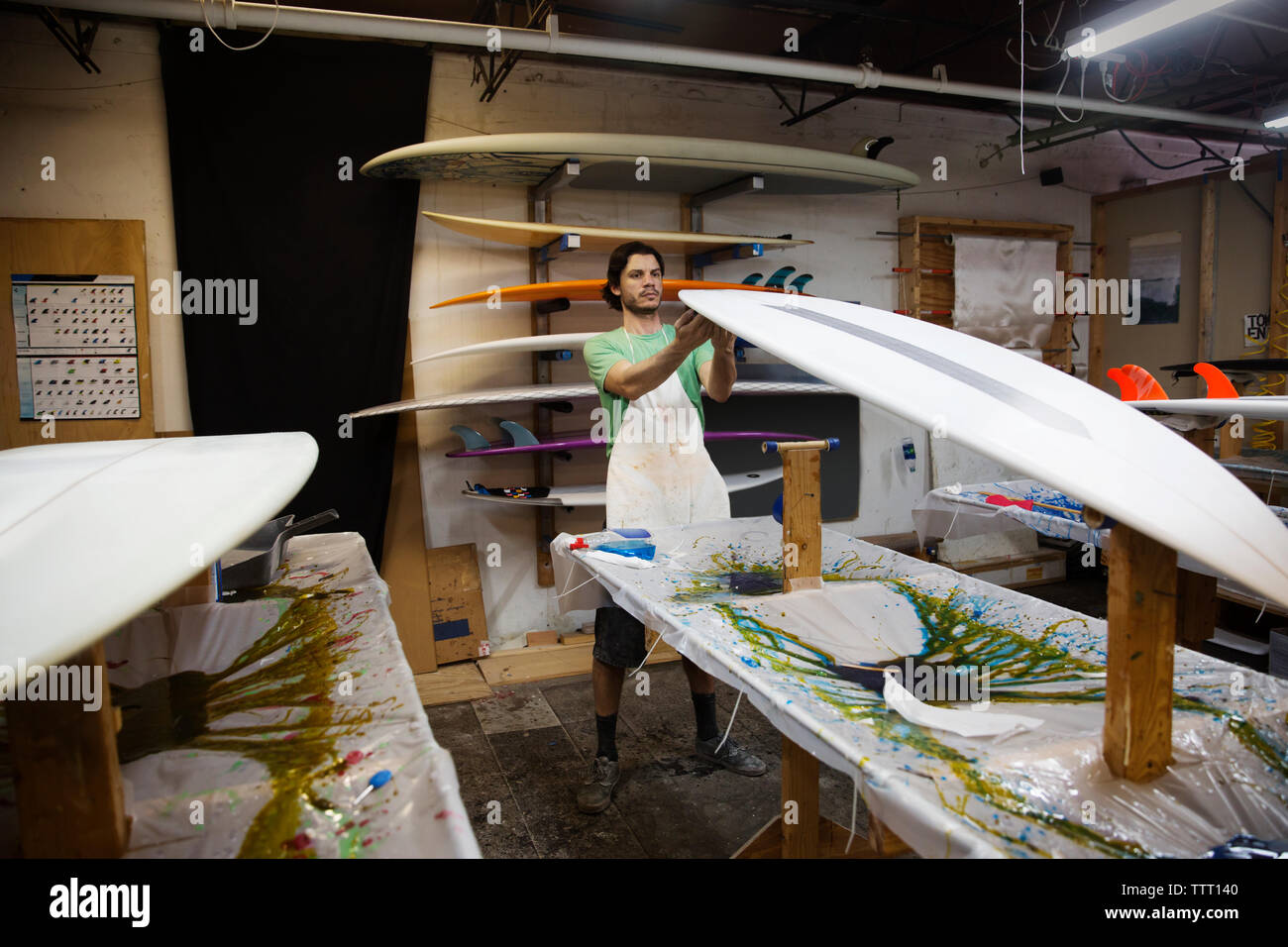 worker examining surfboard in workshop Stock Photo