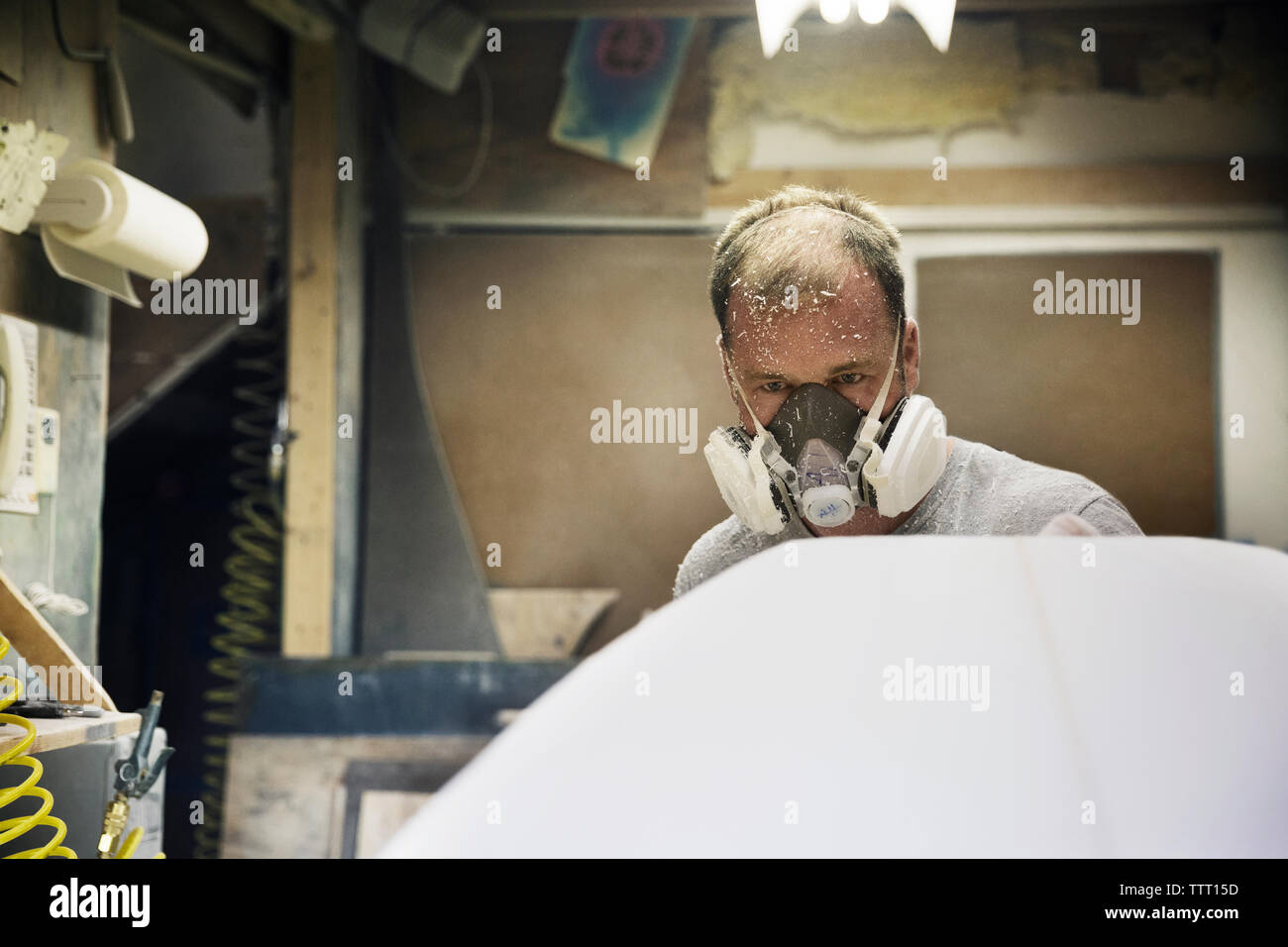 Craftsperson examining surfboard in workshop Stock Photo