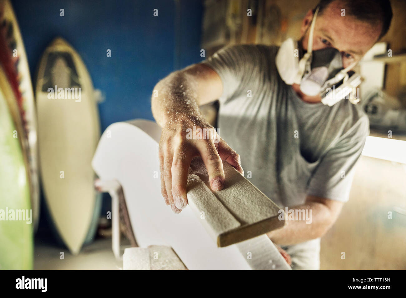 Mid adult man shaping edge of surfboard at Stock Photo Alamy