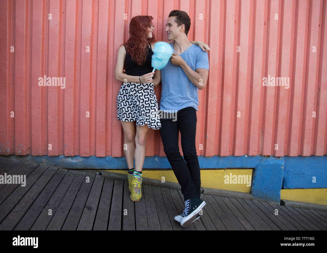 Young couple holding cotton candy while standing against wall Stock Photo