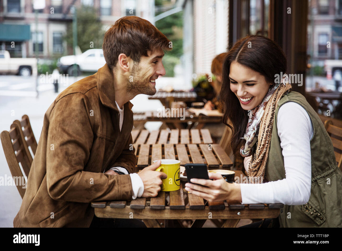 Man looking at girlfriend using mobile phone at cafe Stock Photo