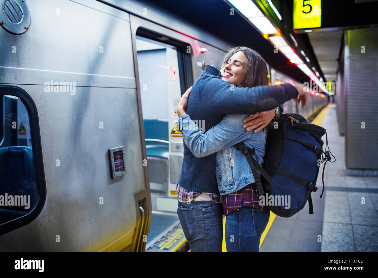 Loving couple embracing while standing at subway station by train Stock Photo