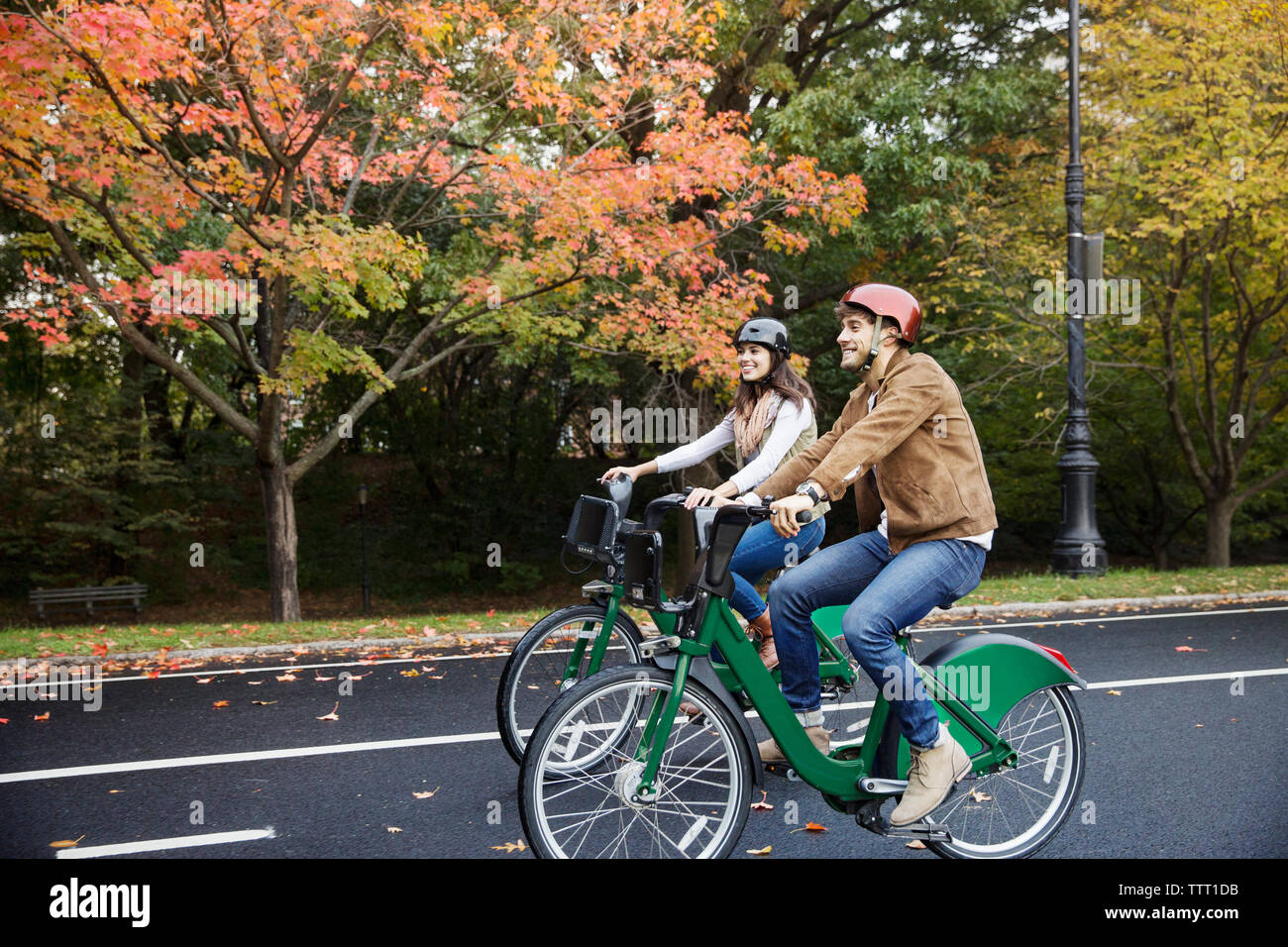 Smiling couple riding bicycle at park Stock Photo