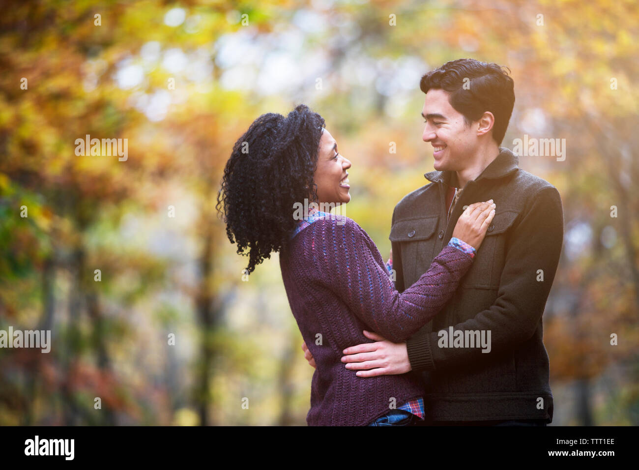 Happy couple looking at each other while standing in forest Stock Photo