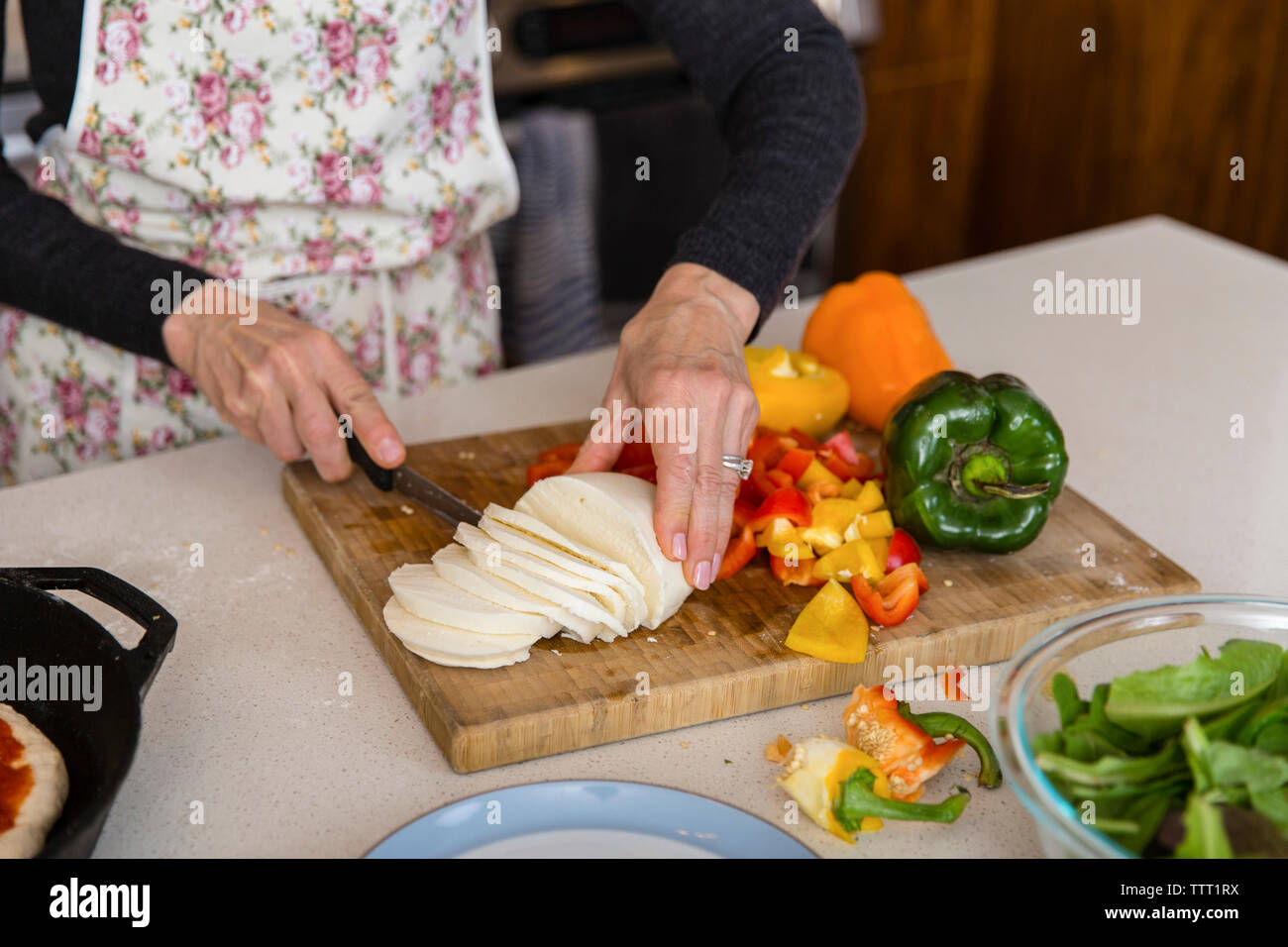 Midsection of woman cutting cheese while preparing food in kitchen at home Stock Photo