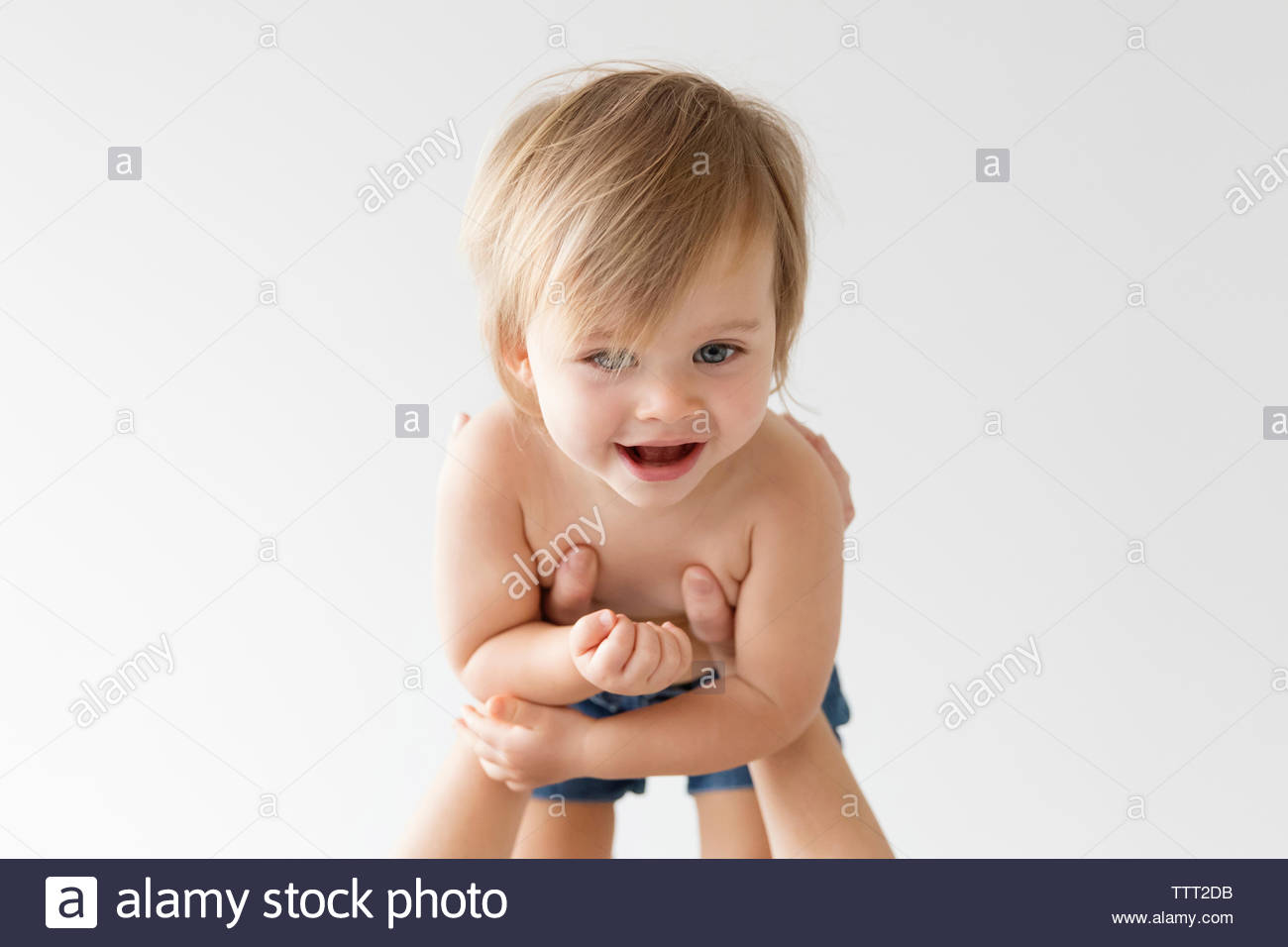 Cropped Hands Of Mother Picking Up Daughter Against White