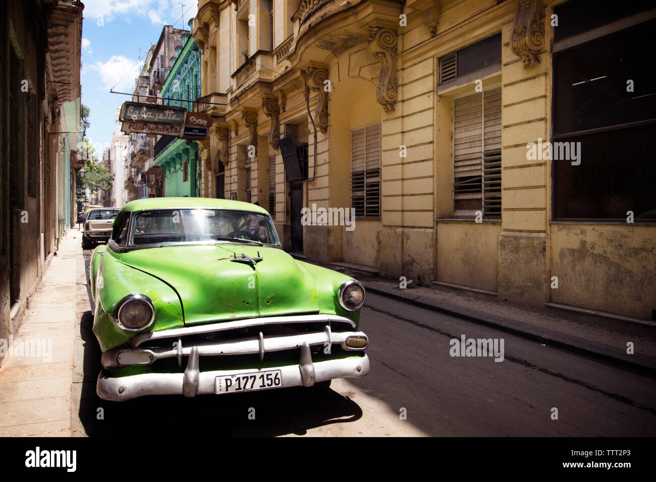 Green vintage car parked on street amidst buildings Stock Photo