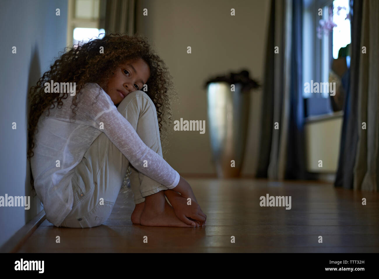 Portrait of sad girl sitting on floor at home Stock Photo - Alamy