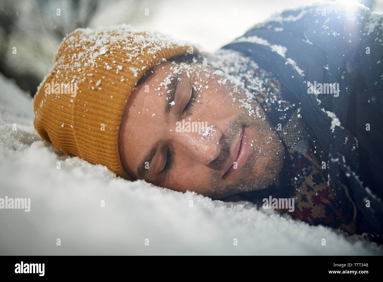 Close-up of man napping on snow covered car bonnet during snowfall Stock Photo