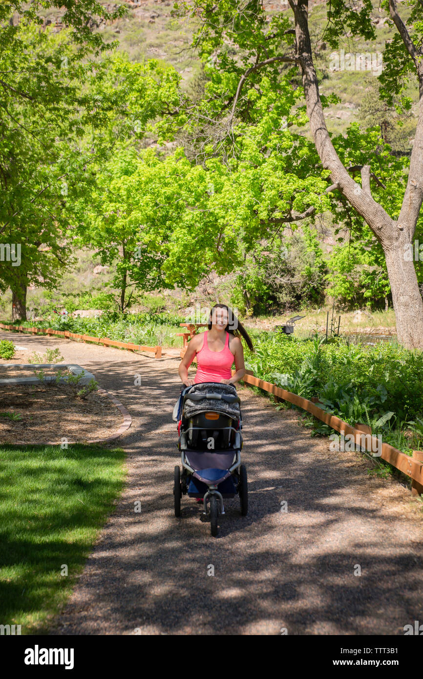 Stroller Walk Woman with baby stroller walking on footpath at park during summer ...