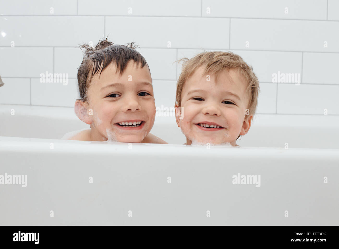 Brothers with big smiles taking a bubble bath Stock Photo