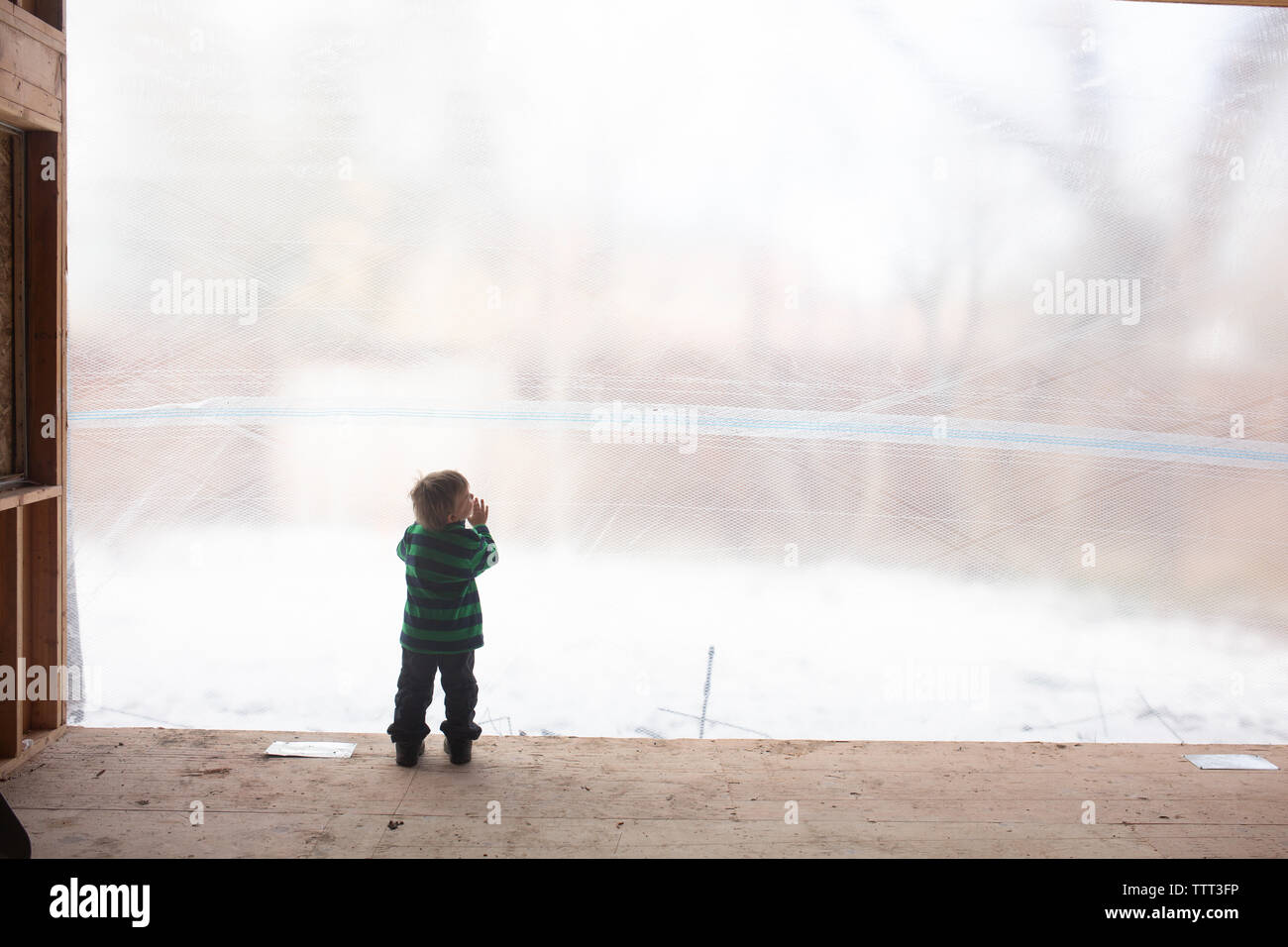 Little boy looking at construction site through big hole Stock Photo