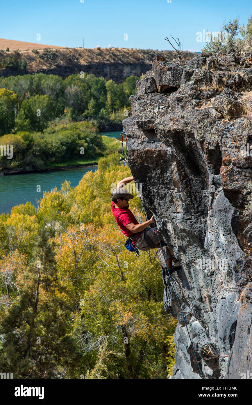 High angle view of man climbing on rock against clear sky Stock Photo