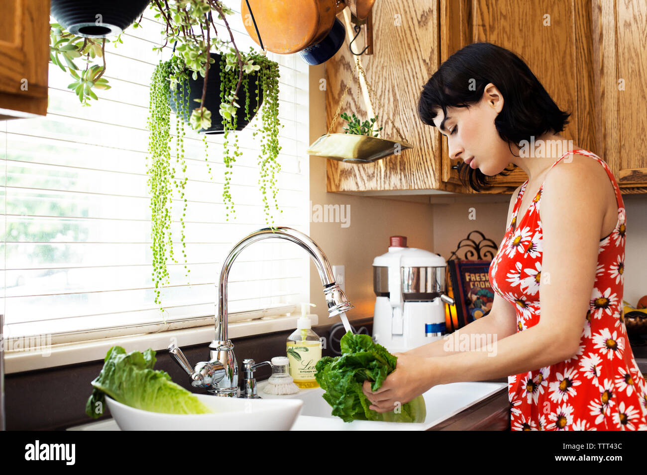 Side view of woman washing lettuce in kitchen sink Stock Photo