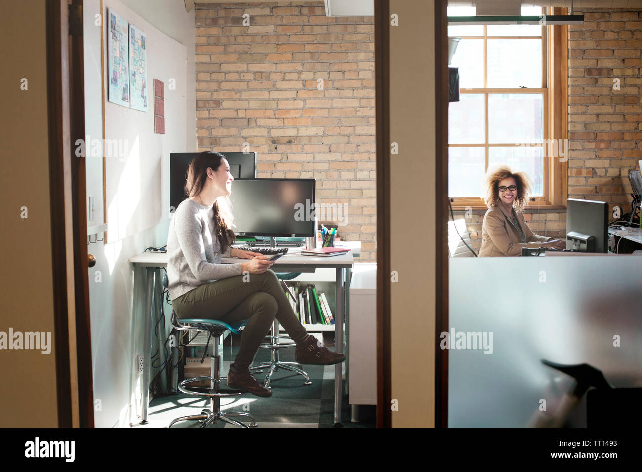 Happy businesswomen talking in creative office Stock Photo