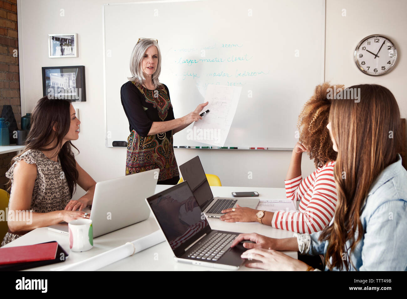 Mature businesswoman giving presentation to female executives in board room Stock Photo