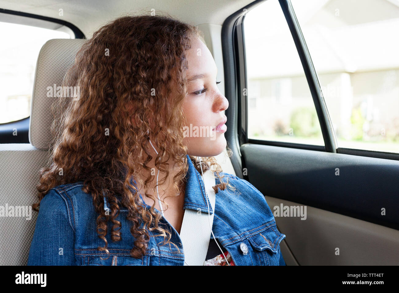 Teenager looking through window while listening music in car Stock Photo