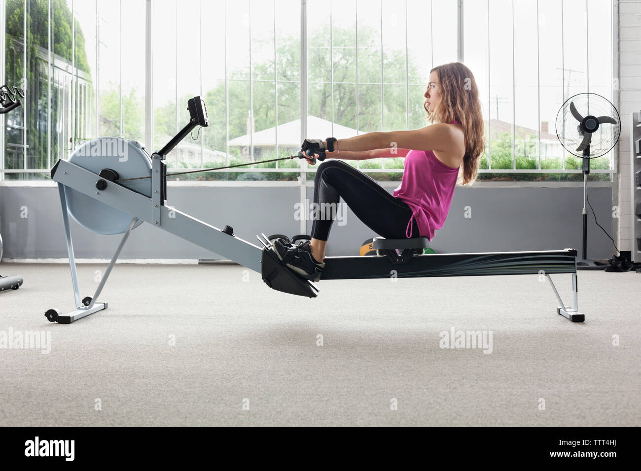 Woman exercising on rowing machine in gym Stock Photo