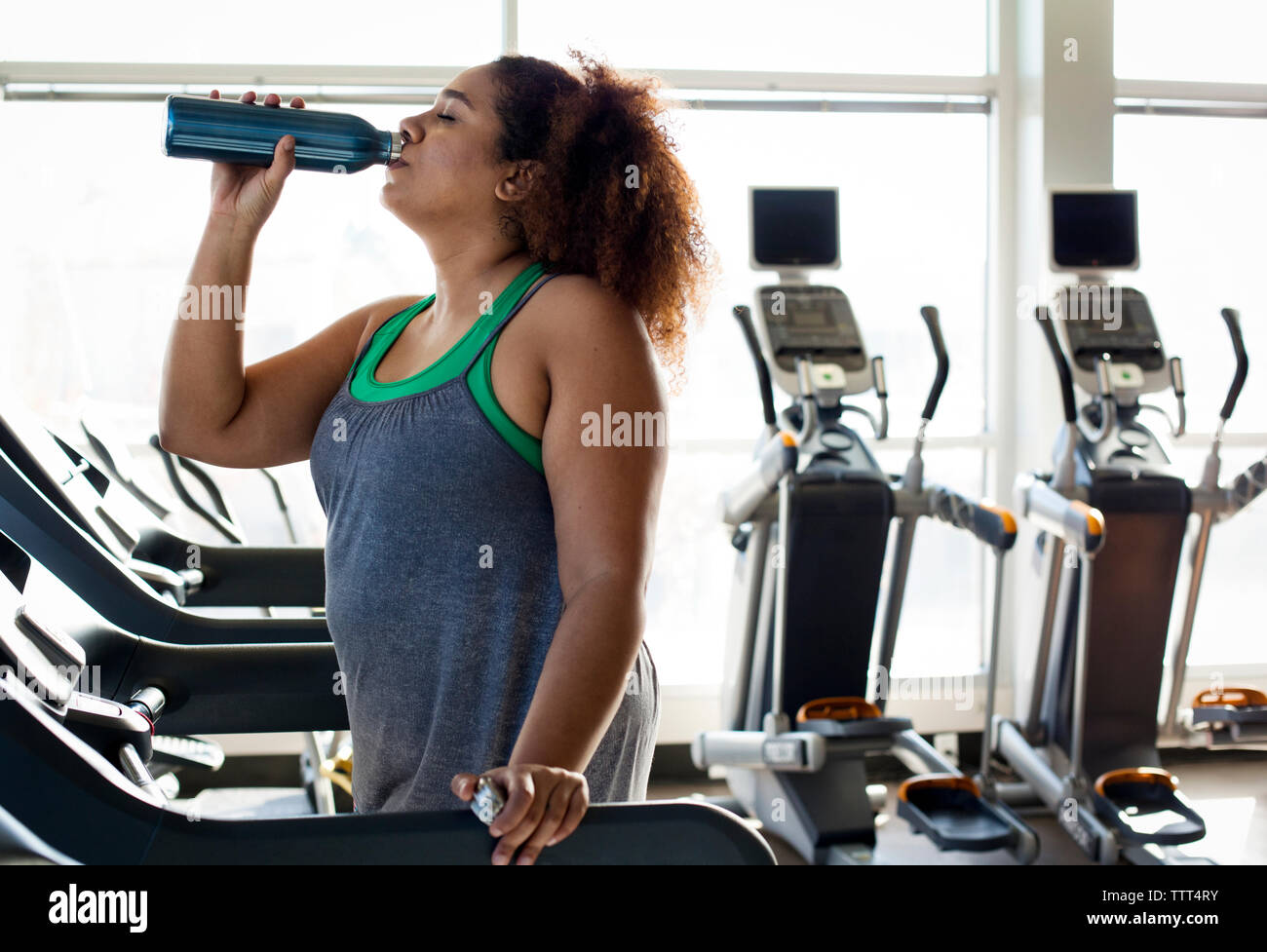 Woman drinking water while standing on treadmill in gym Stock Photo Alamy