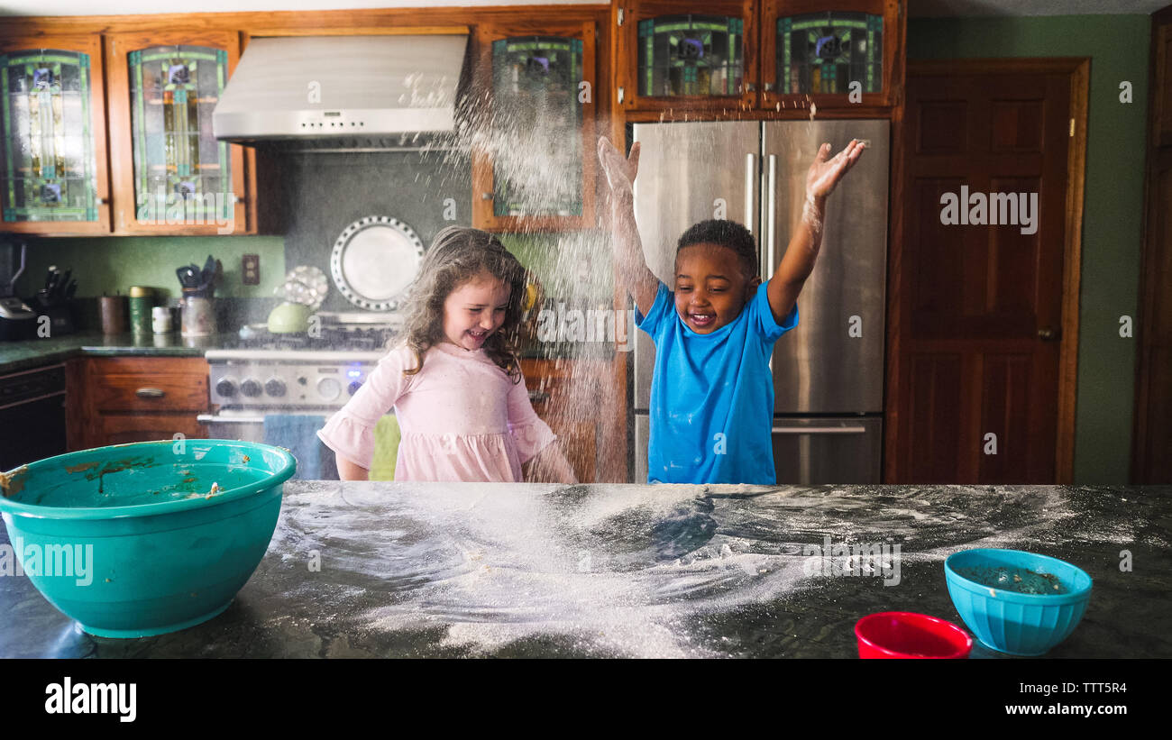 Boy and girl throwing flour in the air in the kitchen Stock Photo