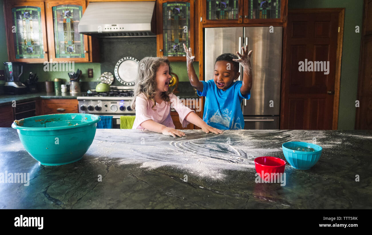 Girl laughing at boy while they make a mess in the kitchen Stock Photo