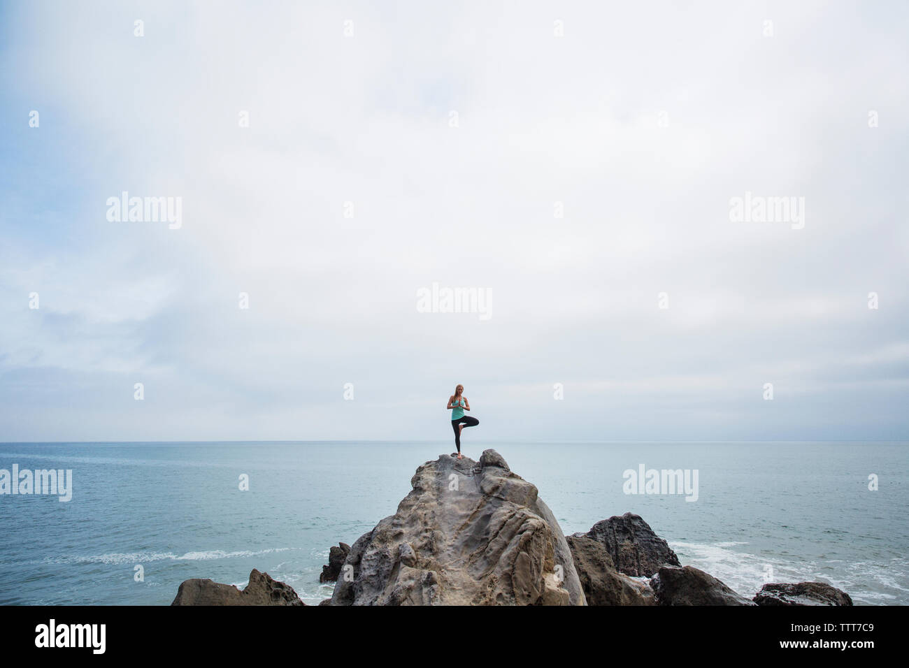 Woman exercising on rocks in sea Stock Photo