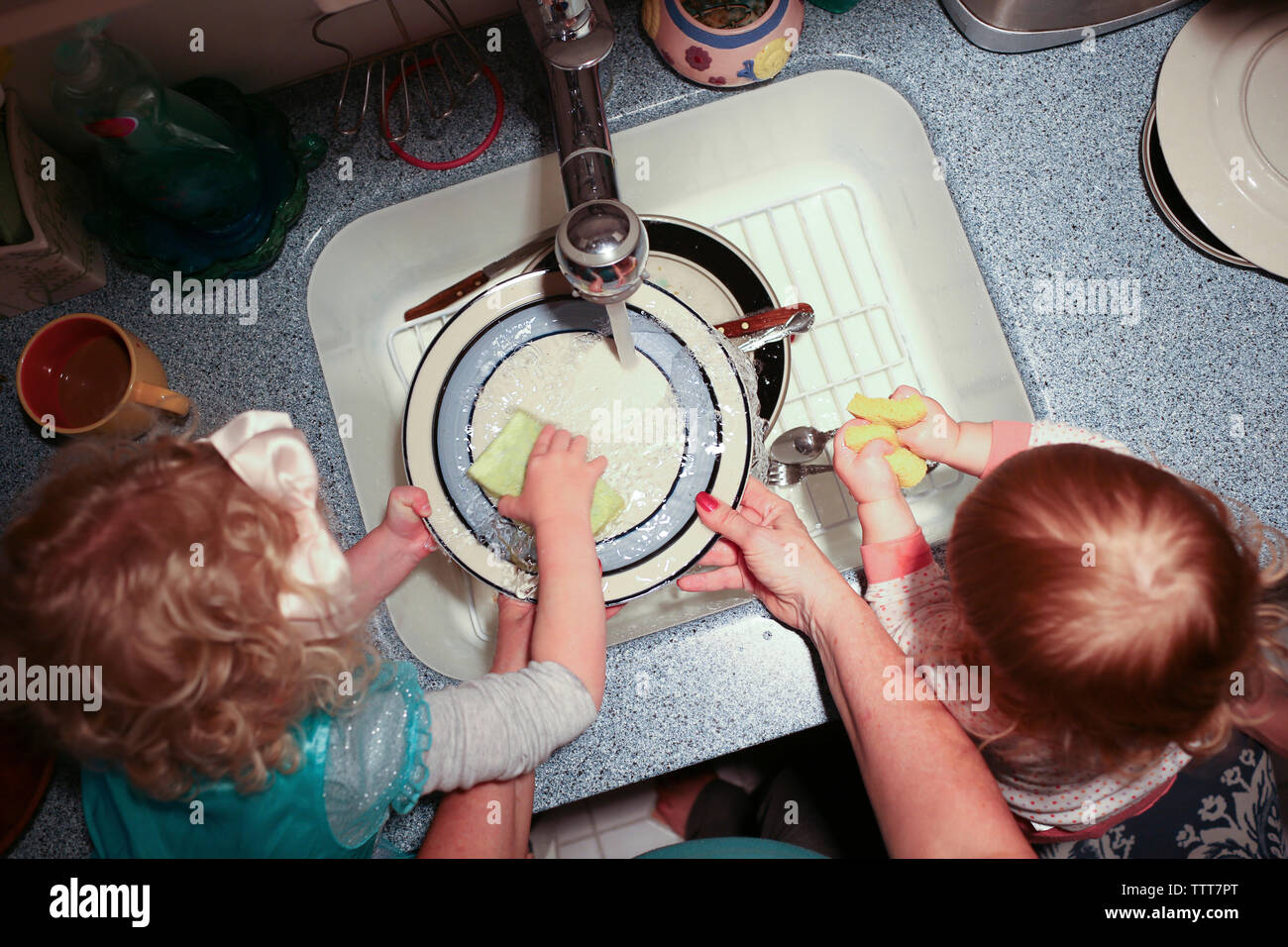 Cropped hands of grandmother with grandchildren washing plates in kitchen Stock Photo