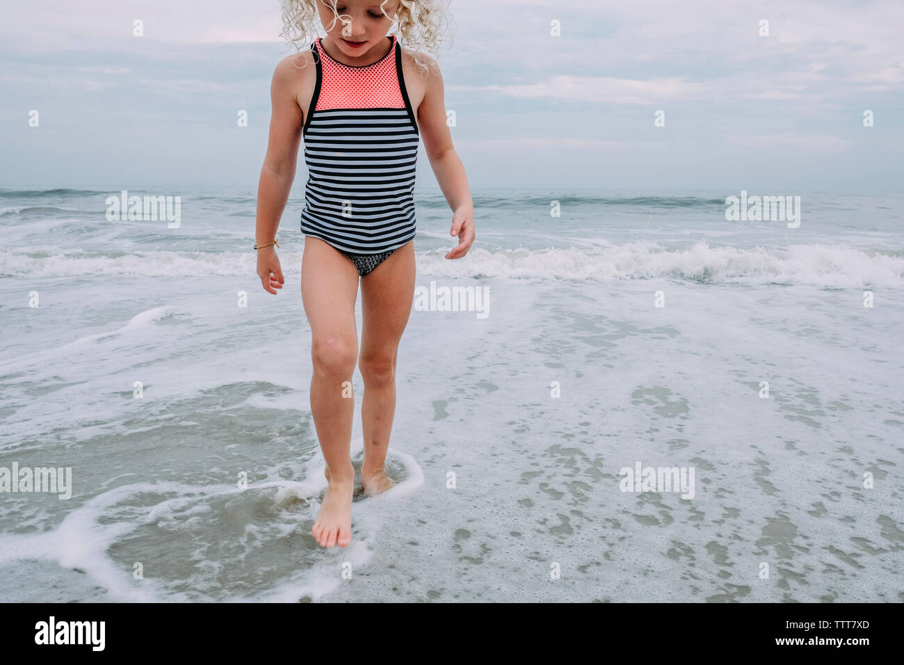Girl playing in waves at Cape May Beach against sky Stock Photo