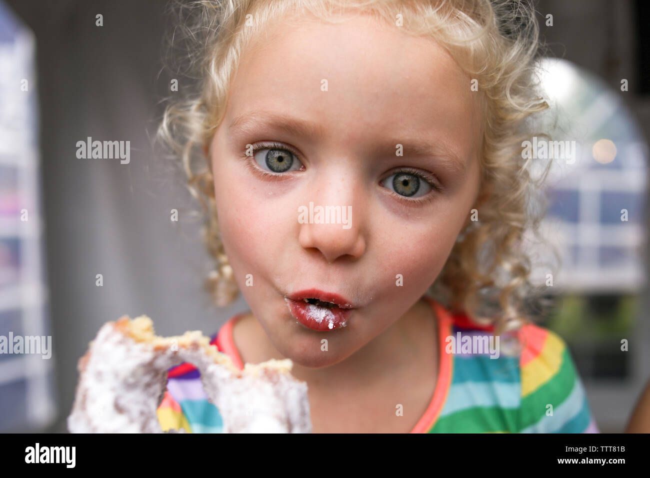 Portrait of cute girl making face while eating donut Stock Photo