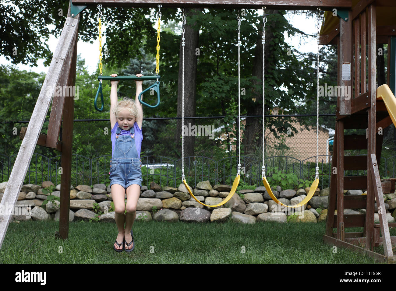 Cute girl hanging on swing at playground Stock Photo