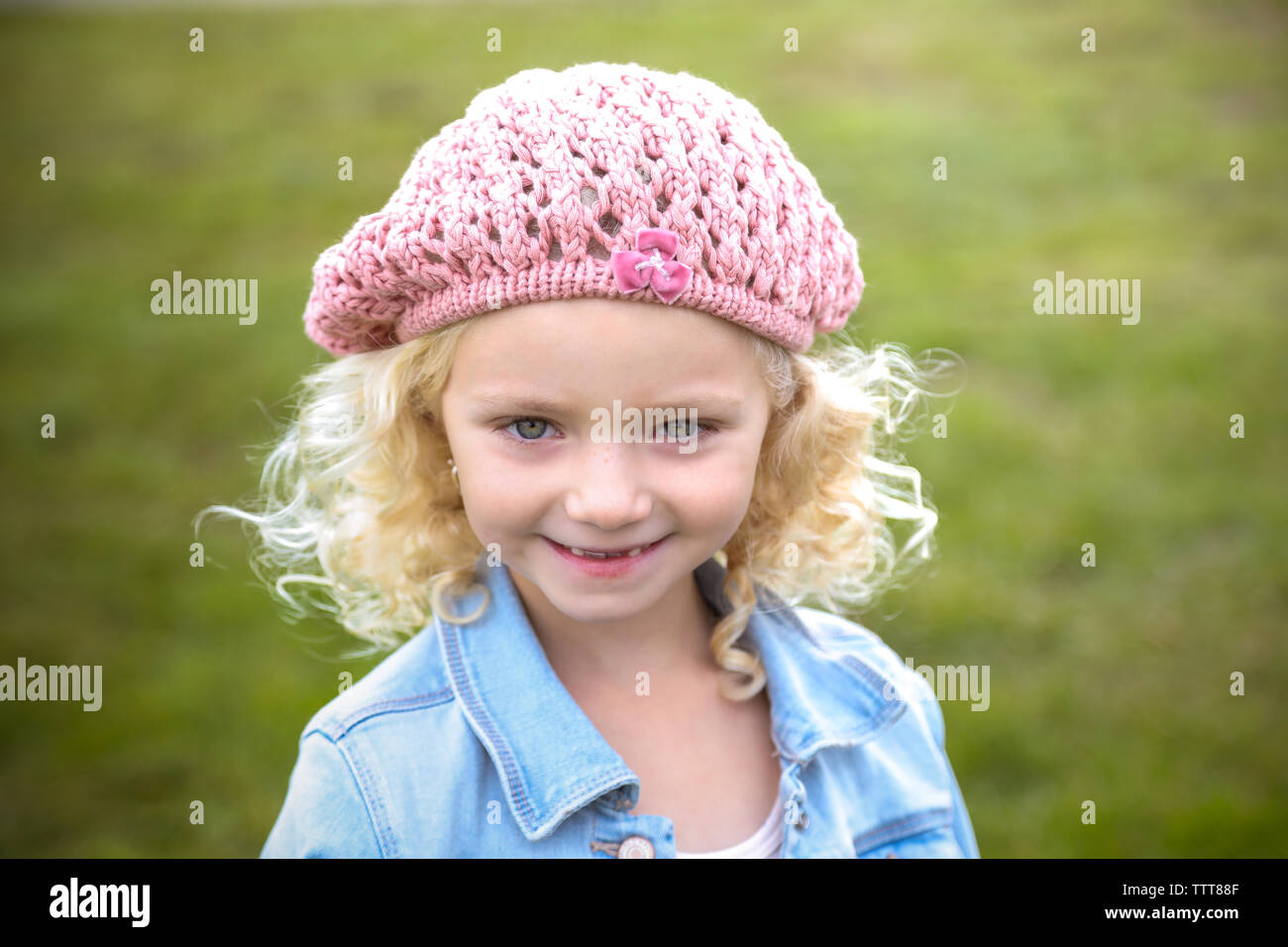 young girl with blonde hair in hat smiling with missing front teeth Stock Photo
