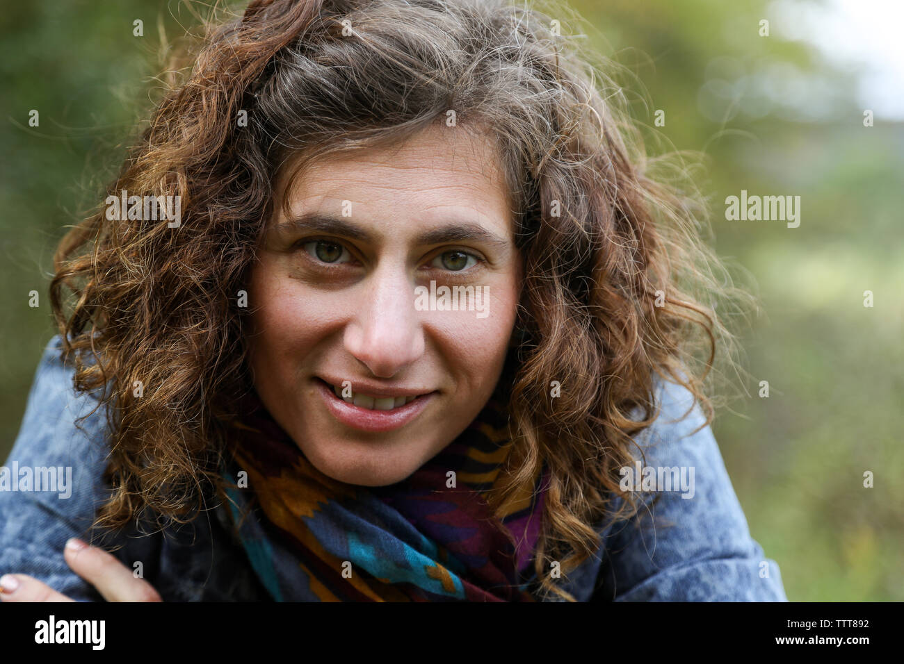 close up of woman with curly brown hair wearing scarf Stock Photo