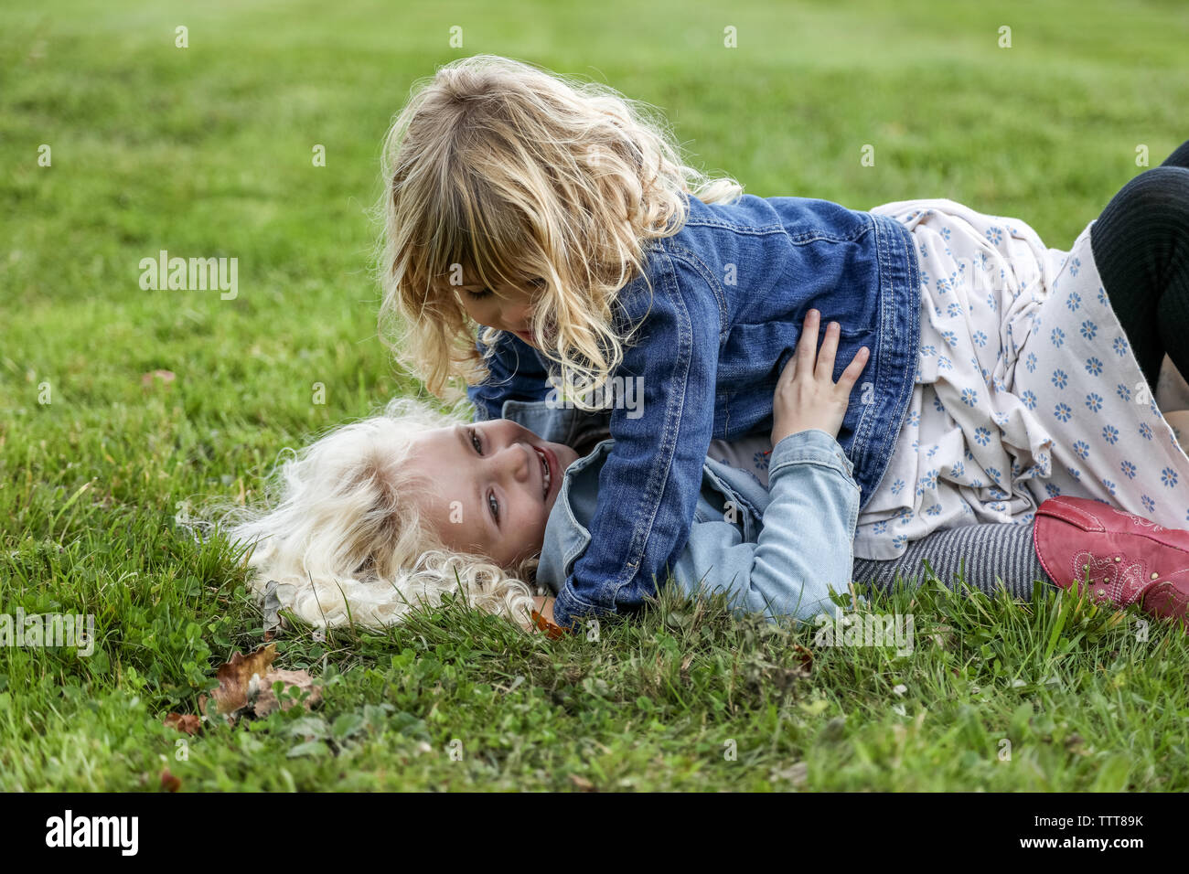 two sisters laying on the grass laughing and playing together Stock Photo